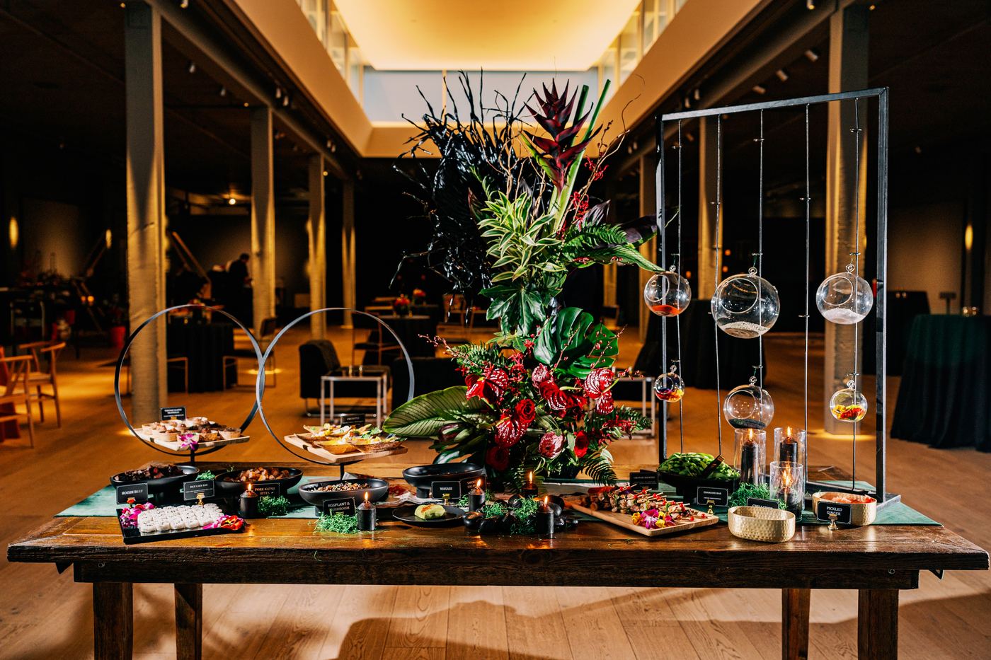 Elaborate catering and floral display table at Palladian Arthouse with tropical arrangements and glass orbs