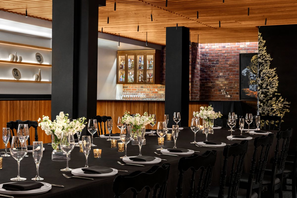 Cellar on 2nd private dining room with long black linen banquet table and white floral centerpieces