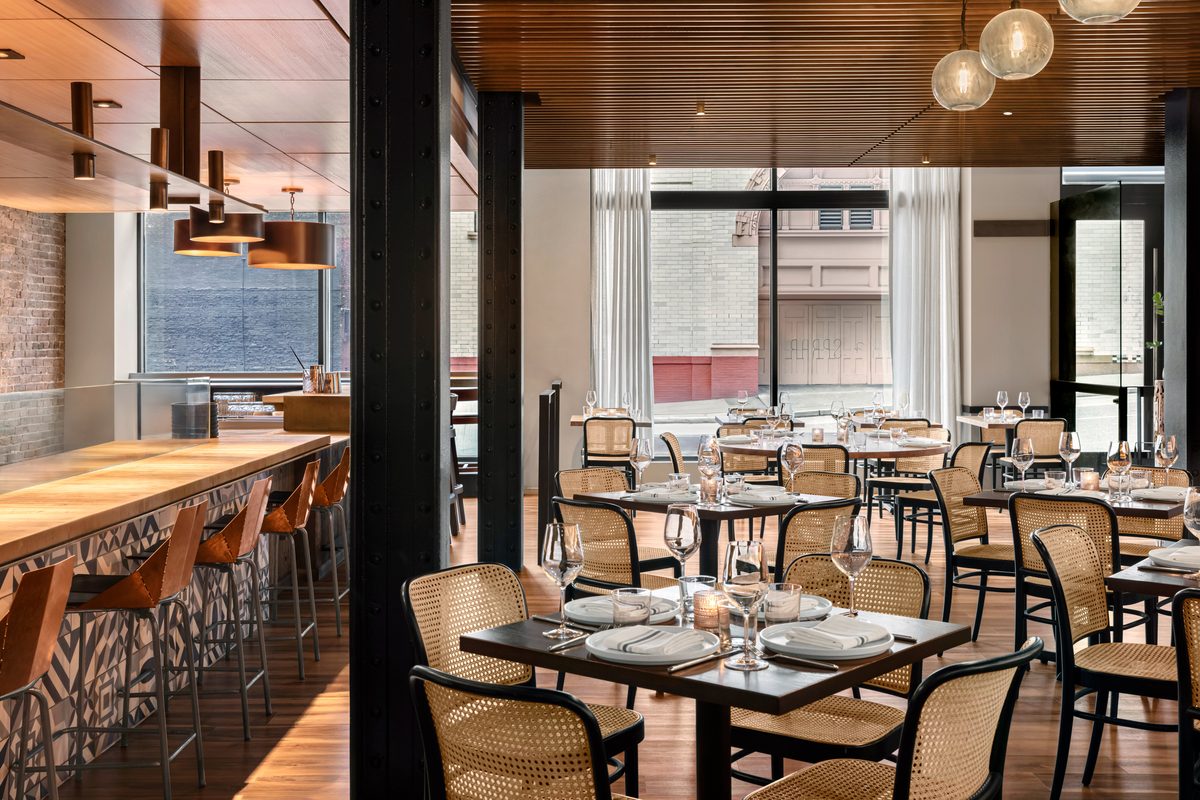 Shaker and Spear private dining room with warm wood tones, rattan chairs and copper pendant lights